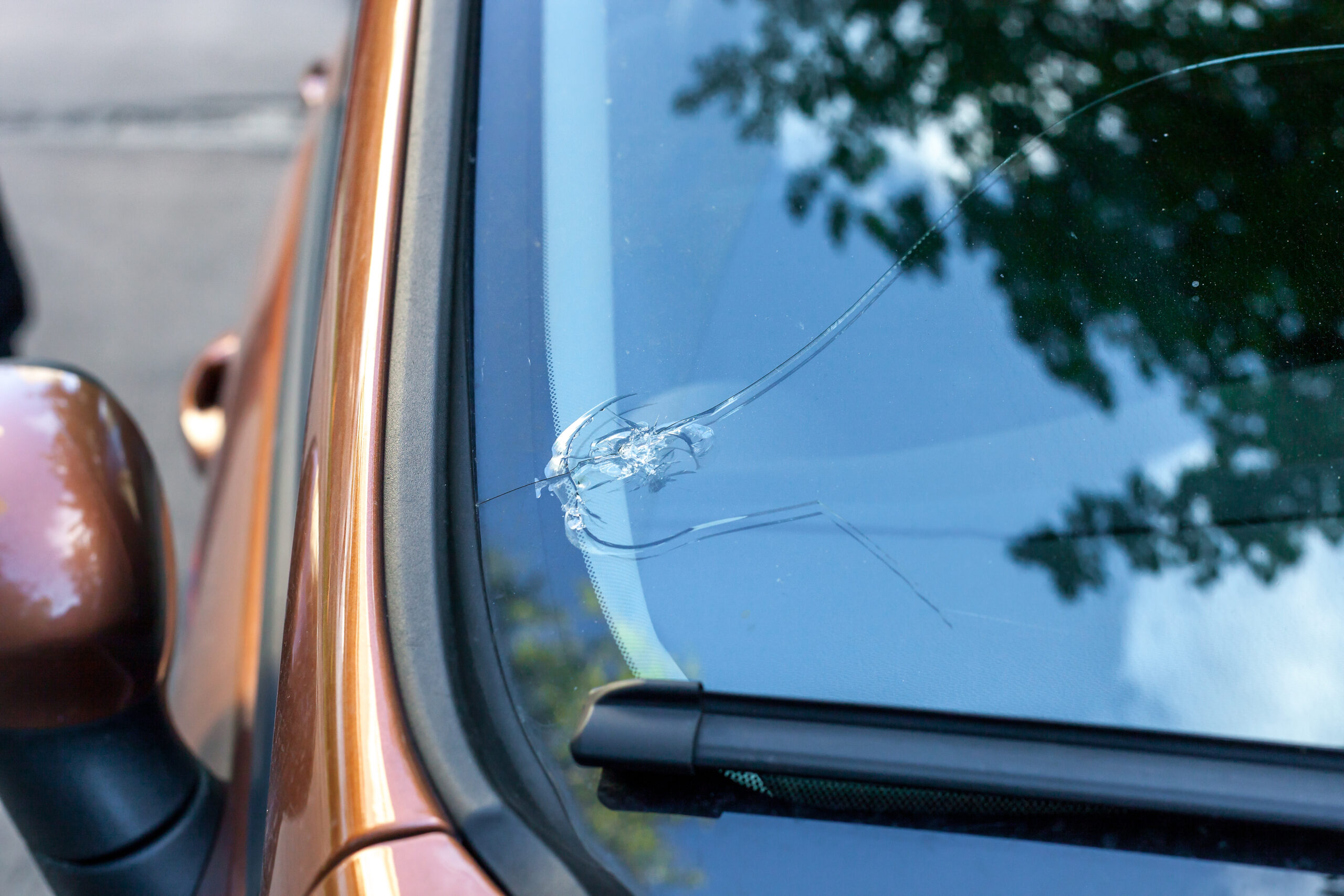 Broken car windshield glass from stone. Damaged windscreen on vehicle, close up